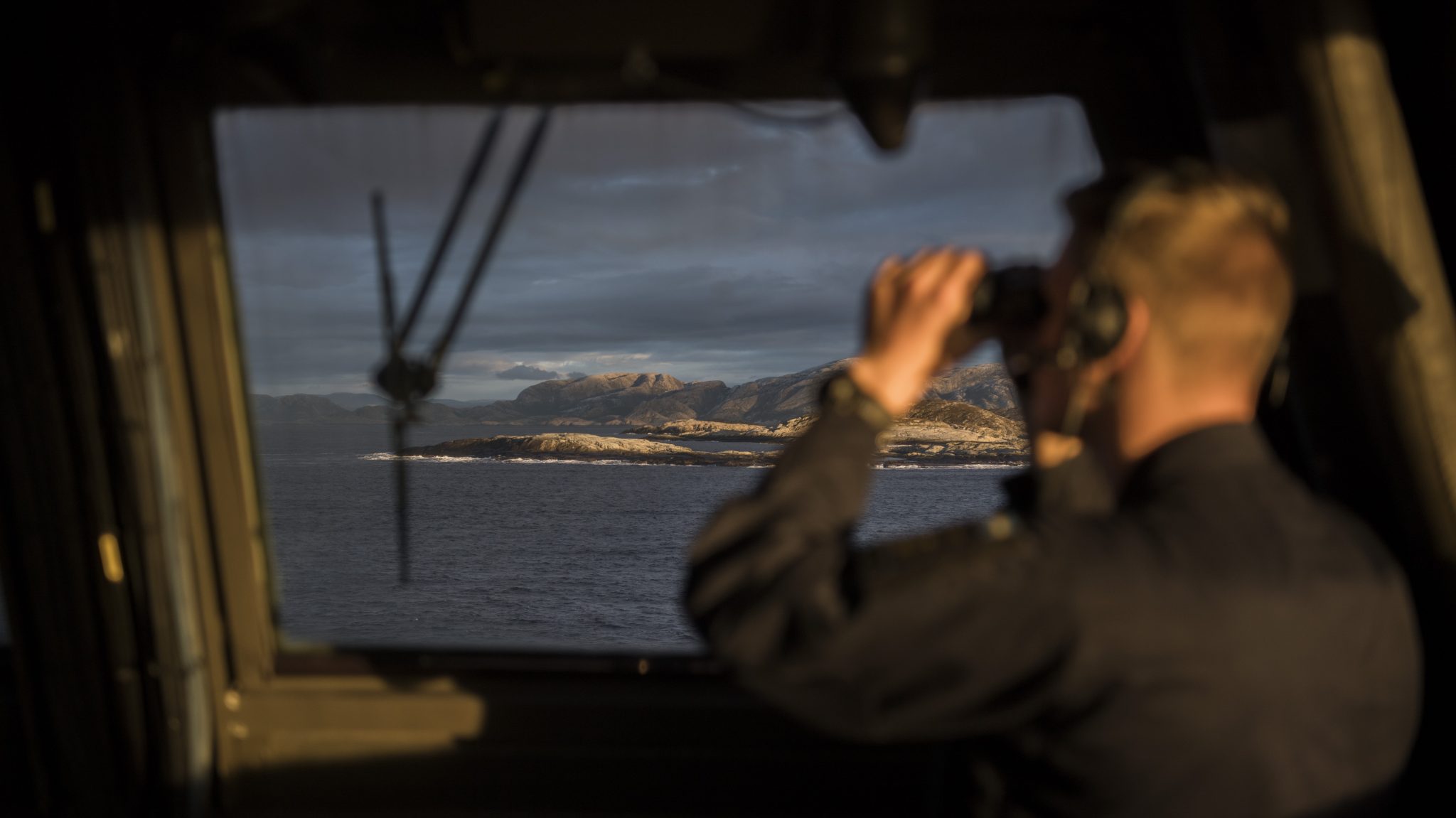Sjöman spejar ut från brygga med kikare