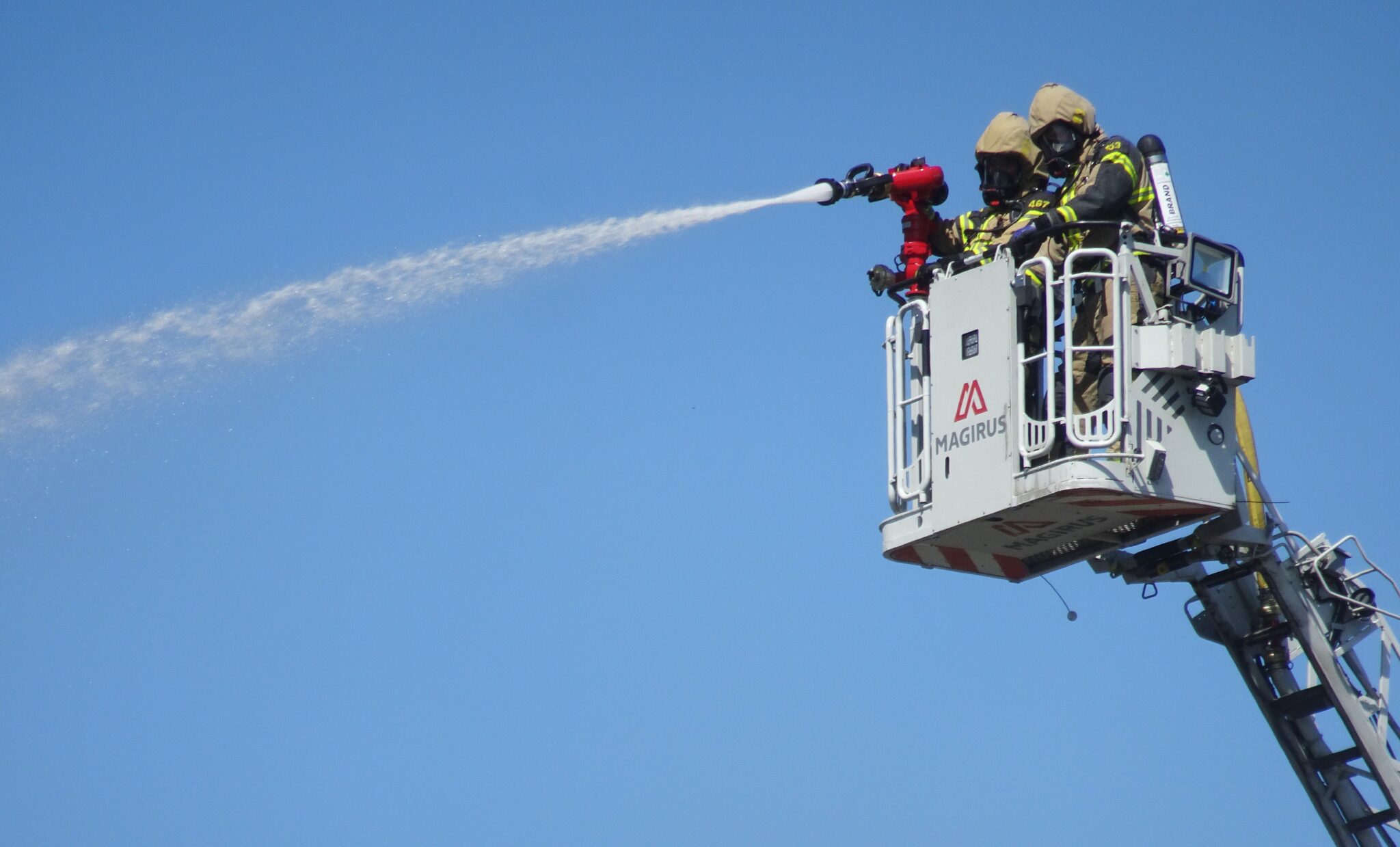 Brandmän på brandstege i luften som släcker en brand
